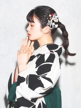 着物と袴のレンタルセット商品画像。袴は緑色。着物は黒色。鶴×矢羽根柄のデザイン。上半身アップ画像。