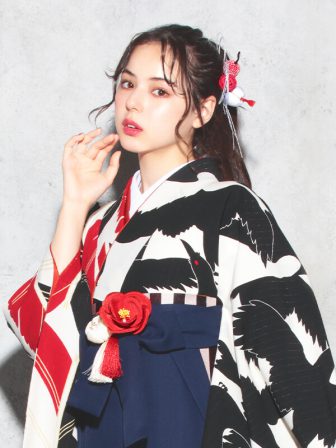 着物と袴のレンタルセット商品画像。袴は紺色。着物はオフ色。烏×矢羽根柄のデザイン。上半身アップ画像。